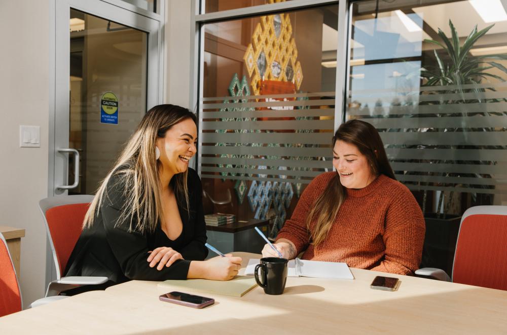 Two women sitting at a desk in an office.