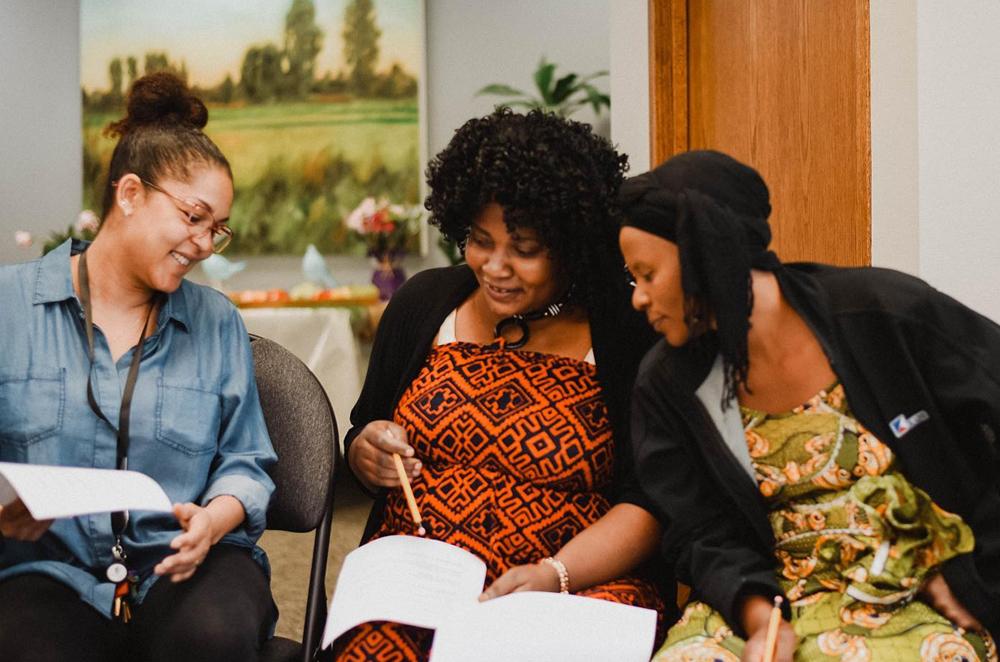 Three Black women sitting together in an office, working together and reading a document