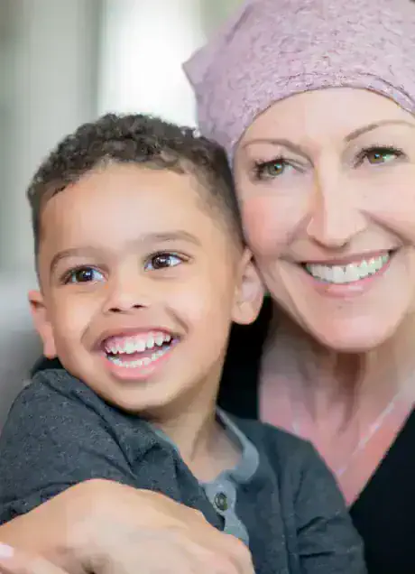 Smiling woman wearing a headscarf hugging a happy young boy