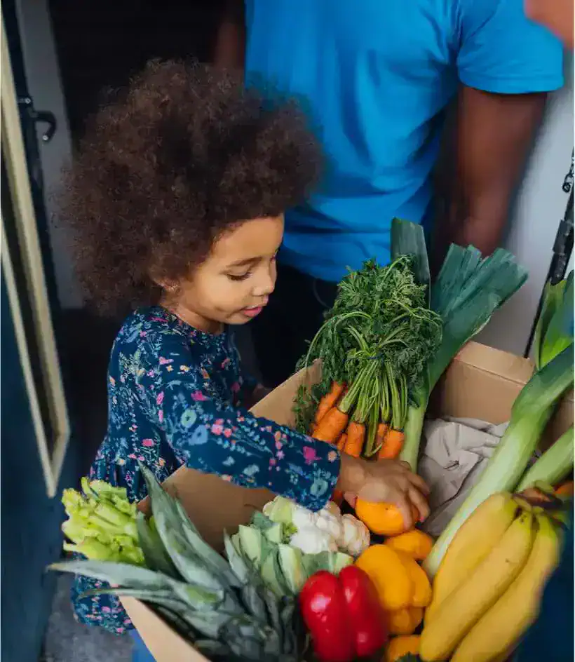 Young girl picking vegetables from a box