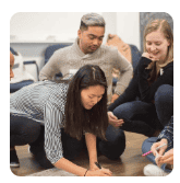 Small group collaborating on a project while writing notes on paper.