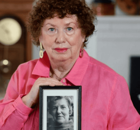 Senior lady holding a framed black and white portrait of another woman.