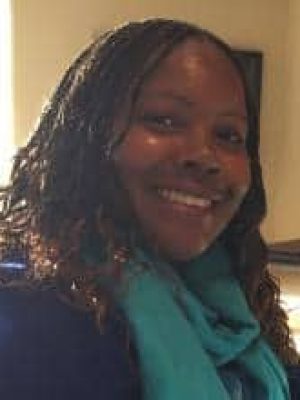 Woman smiling wearing a teal scarf and dark blue sweater.